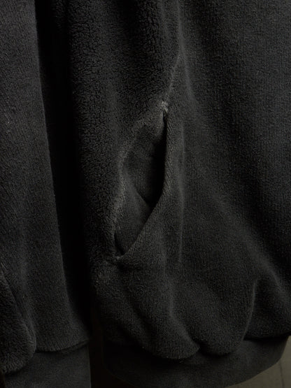 Close-up of a dark charcoal gray plush fleece fabric with a visible stitched pocket opening.