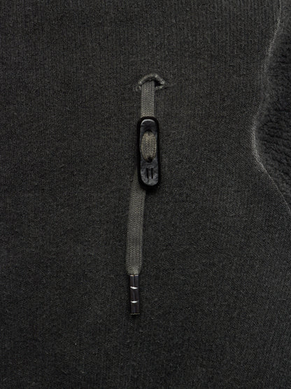 Close-up of a dark charcoal gray knit fabric with a vertical zipper and a small black pull tab.