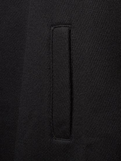 Close-up of a black woven fabric garment showing a vertical welt pocket detail.