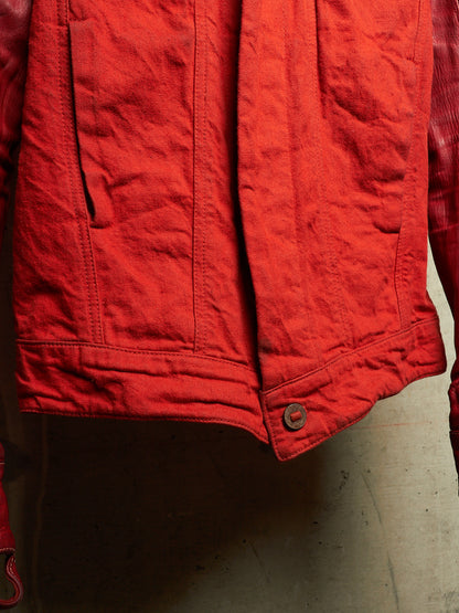 A close-up of a red quilted jacket or vest with visible stitching, a button closure, and a textured fabric surface.