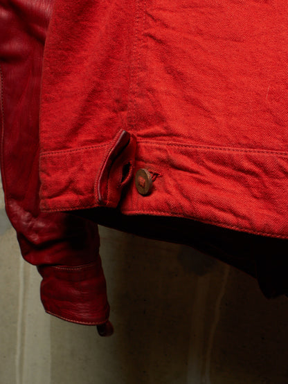 Close-up detail of a red leather jacket showing a buttoned flap pocket and the texture of the red leather.