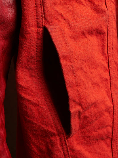 Close-up of a textured red fabric garment with a dark shadowed slit or pocket opening.