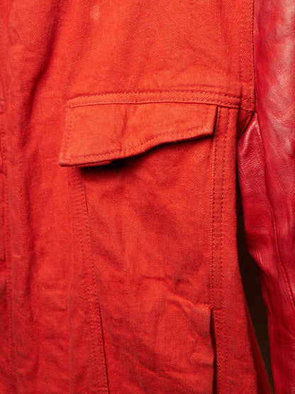 Close-up detail of a red jacket showing a textured canvas flap pocket and smooth leather sleeve.