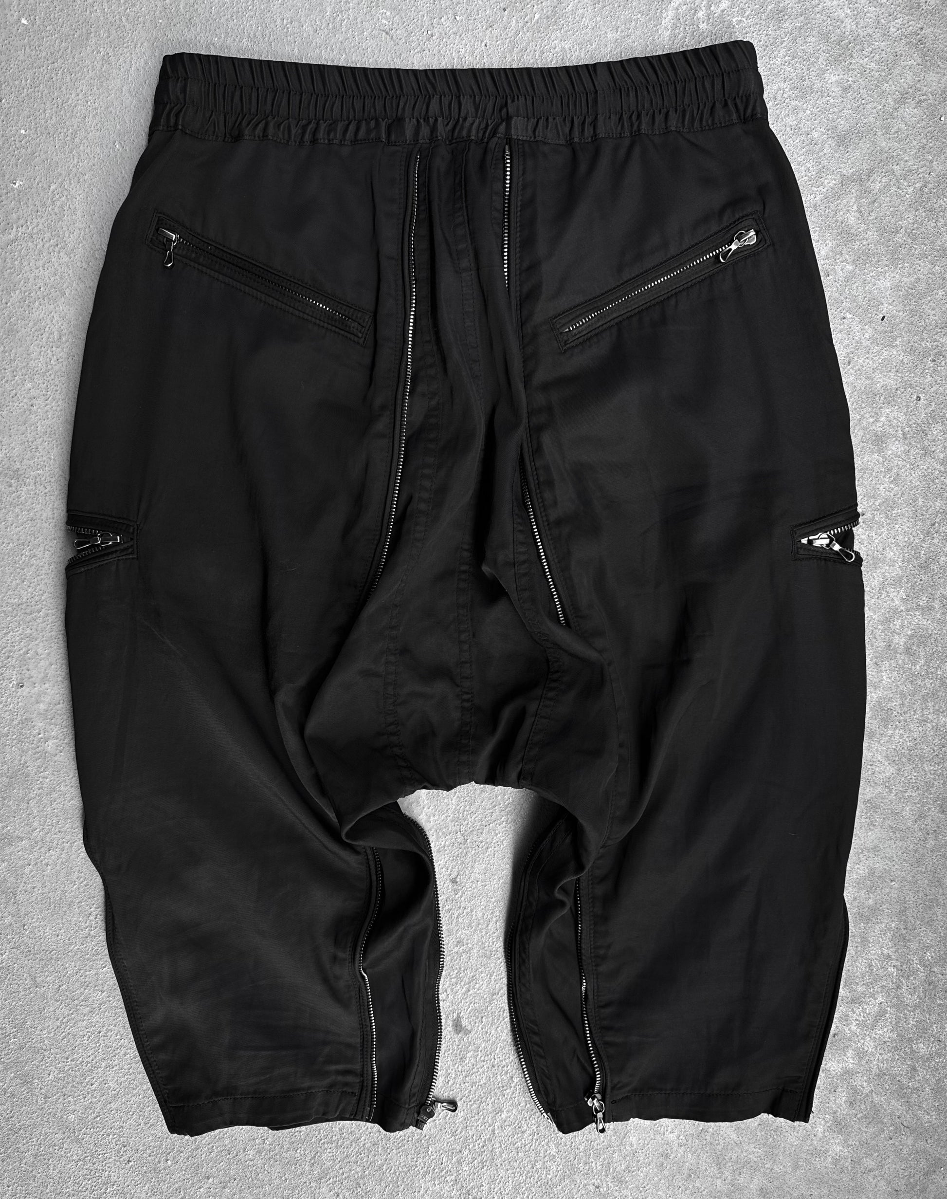 A pair of DRIEW Julius_7 SS10 “neurbanvolker;” Convertible Multi-zip Cotton Twill Shorts, black, size 2 (US 29-32 waist), with multiple silver zippers on pockets and legs, laid flat on a light gray surface in flawless condition.