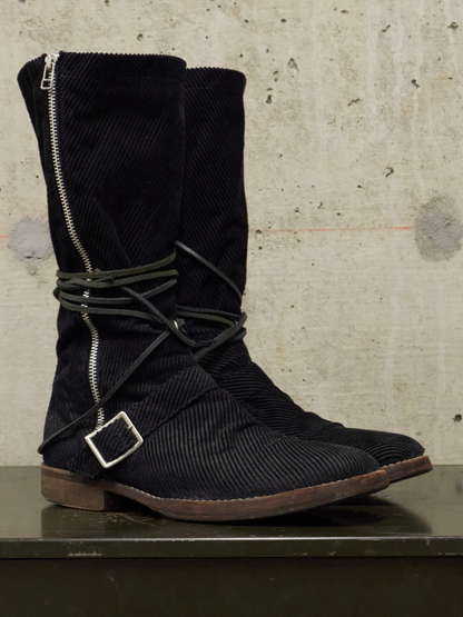Black corduroy boots with buckles on a textured surface