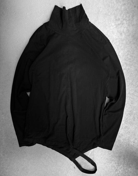 A The Viridi-Anne Ninja High Neck Cotton Long-sleeve shirt in black, size 2, lies flat on a light gray surface with one bottom strap visible; minor fading indicates medium condition.