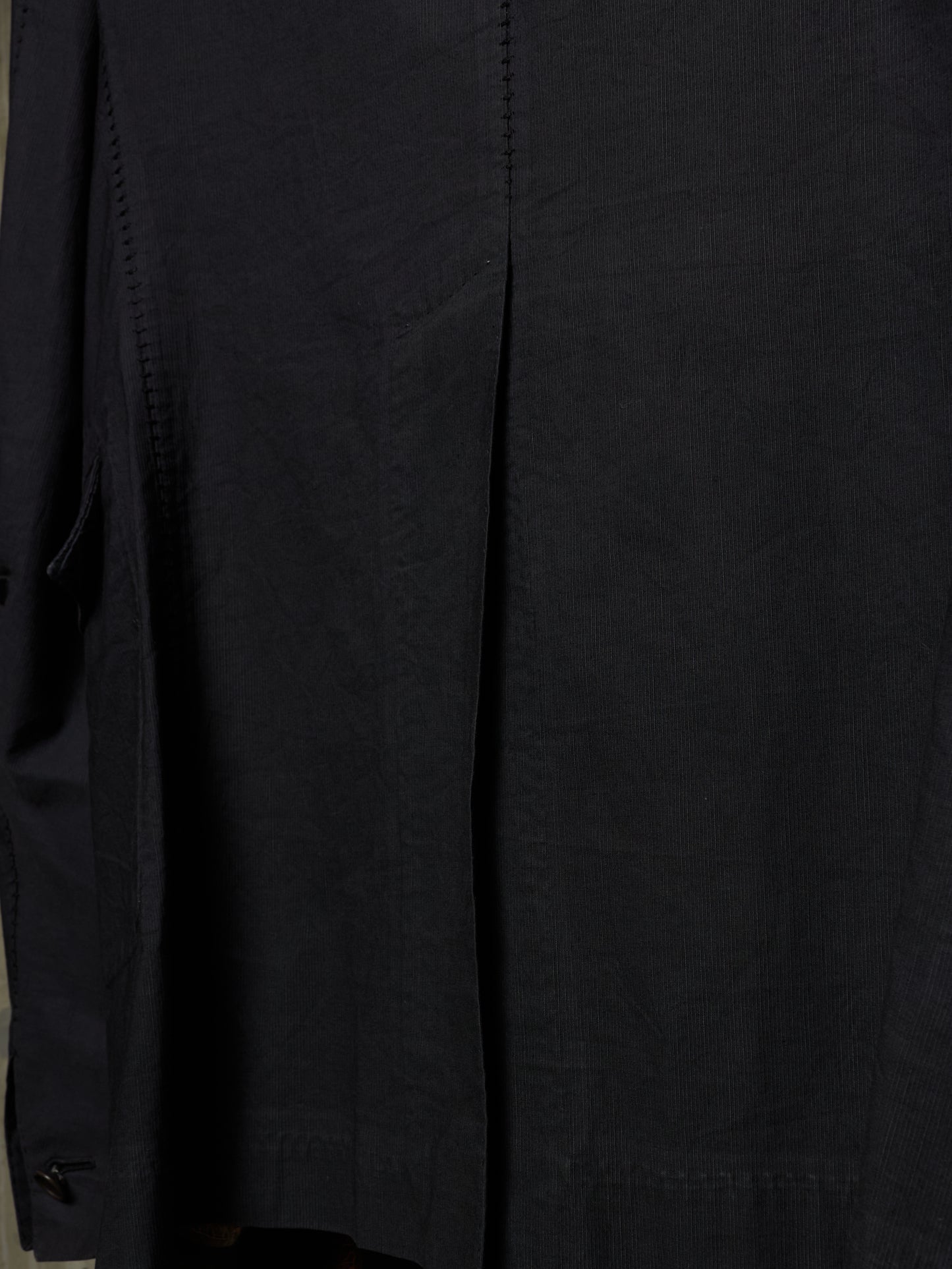 Close-up of a black garment, showing the fabric texture and a vertical seam detail.