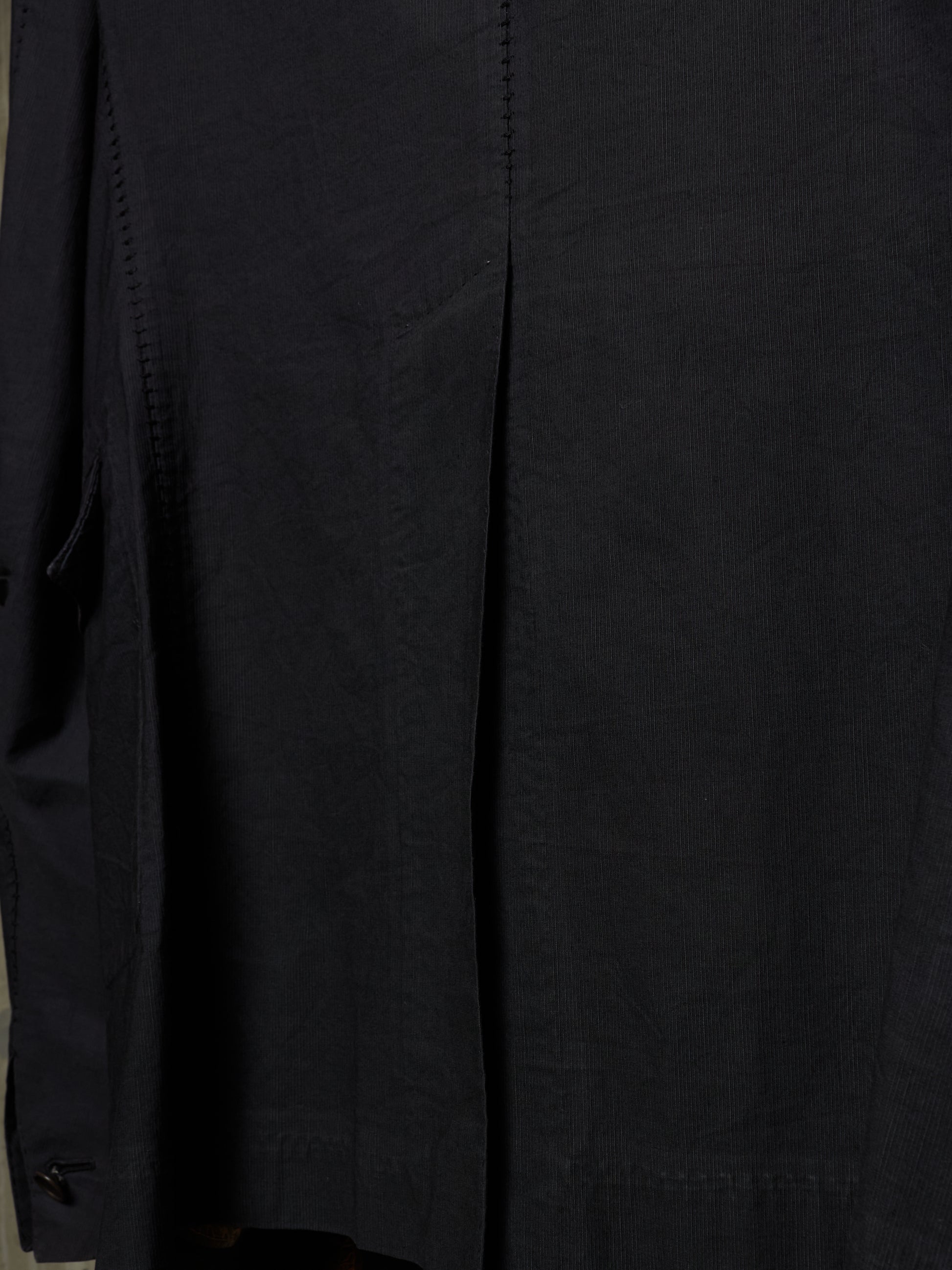 Close-up of a black garment, showing the fabric texture and a vertical seam detail.