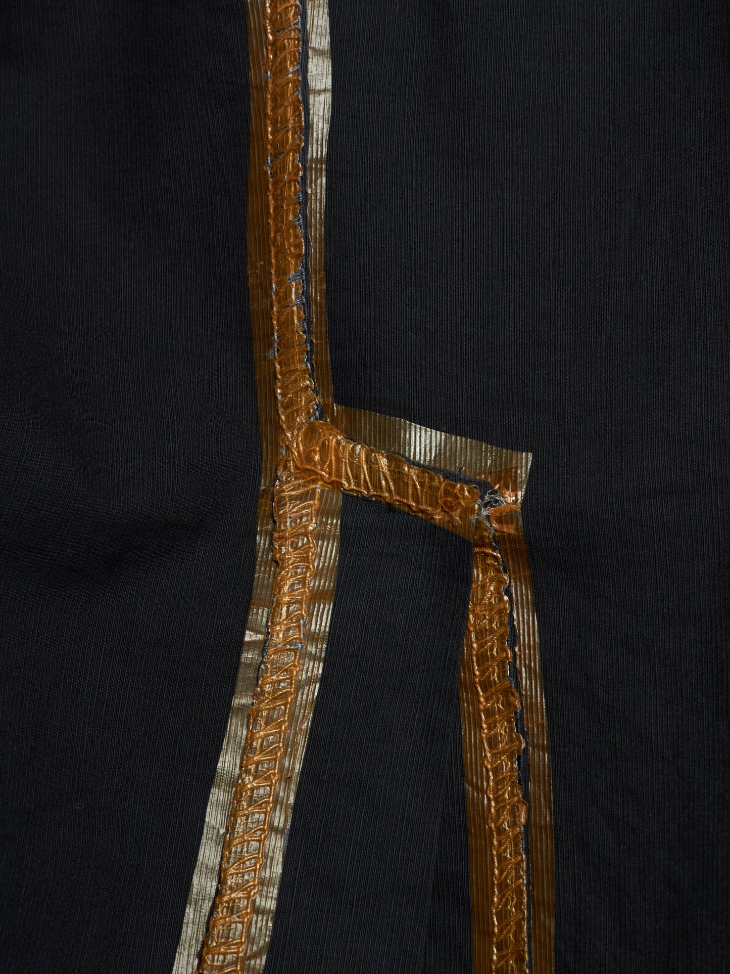 Close-up of a black garment featuring a prominent metallic gold and silver embroidered border detail.