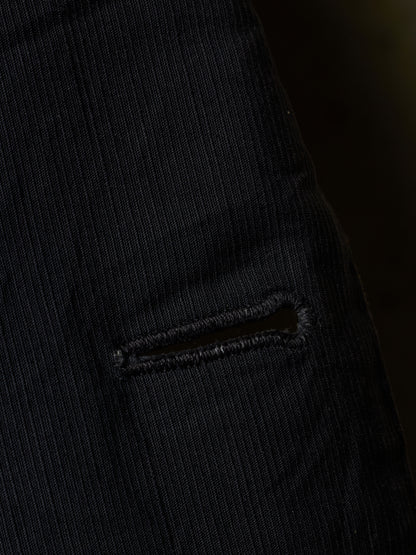 Close-up of a black ribbed corduroy fabric with a small horizontal slit detail.