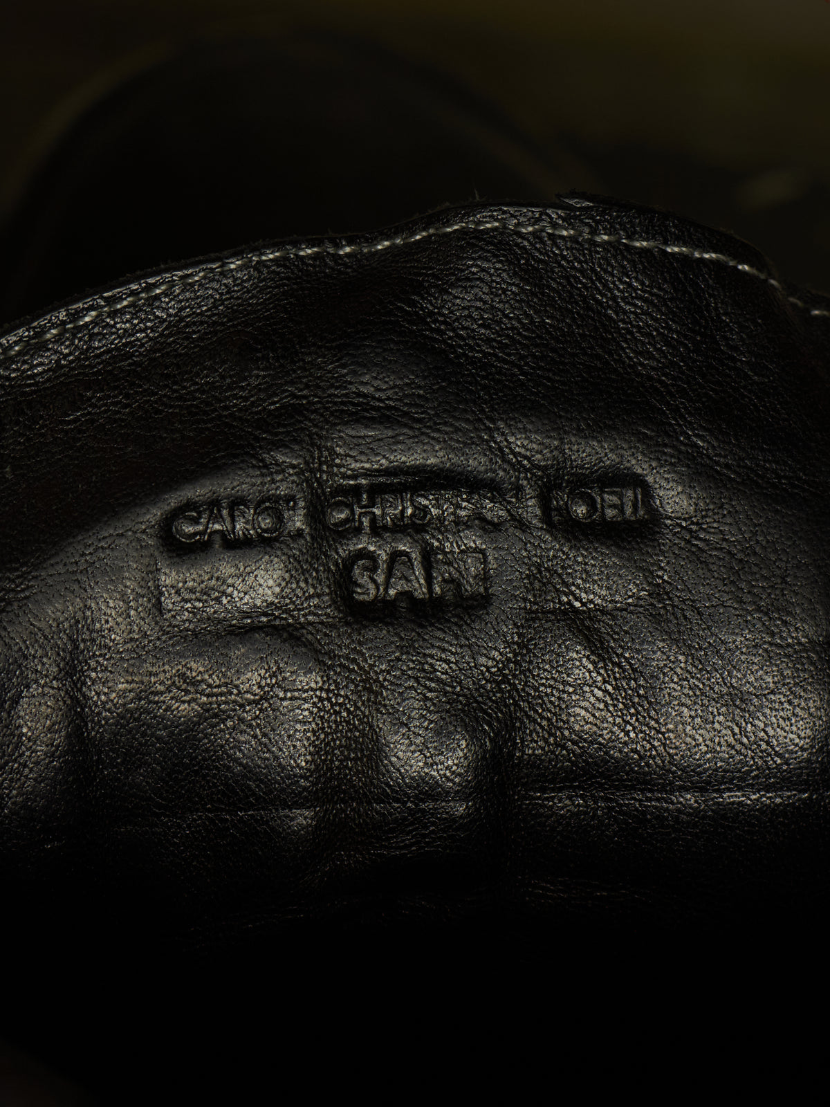 Close-up of a black leather boot interior showing embossed branding text that reads 'CAREY CHRISTOPHER LOEL SALT'.