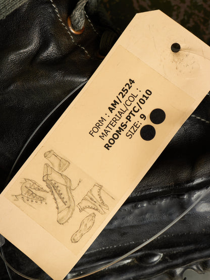 A close-up of a black leather shoe or boot with a beige paper hangtag attached. The tag has printed black text including 'FORM: AW2534', 'MATERIAL/COL: ROOMS-PTC/010', and 'SIZE: 9', plus a faint line drawing of a shoe on the lower left.