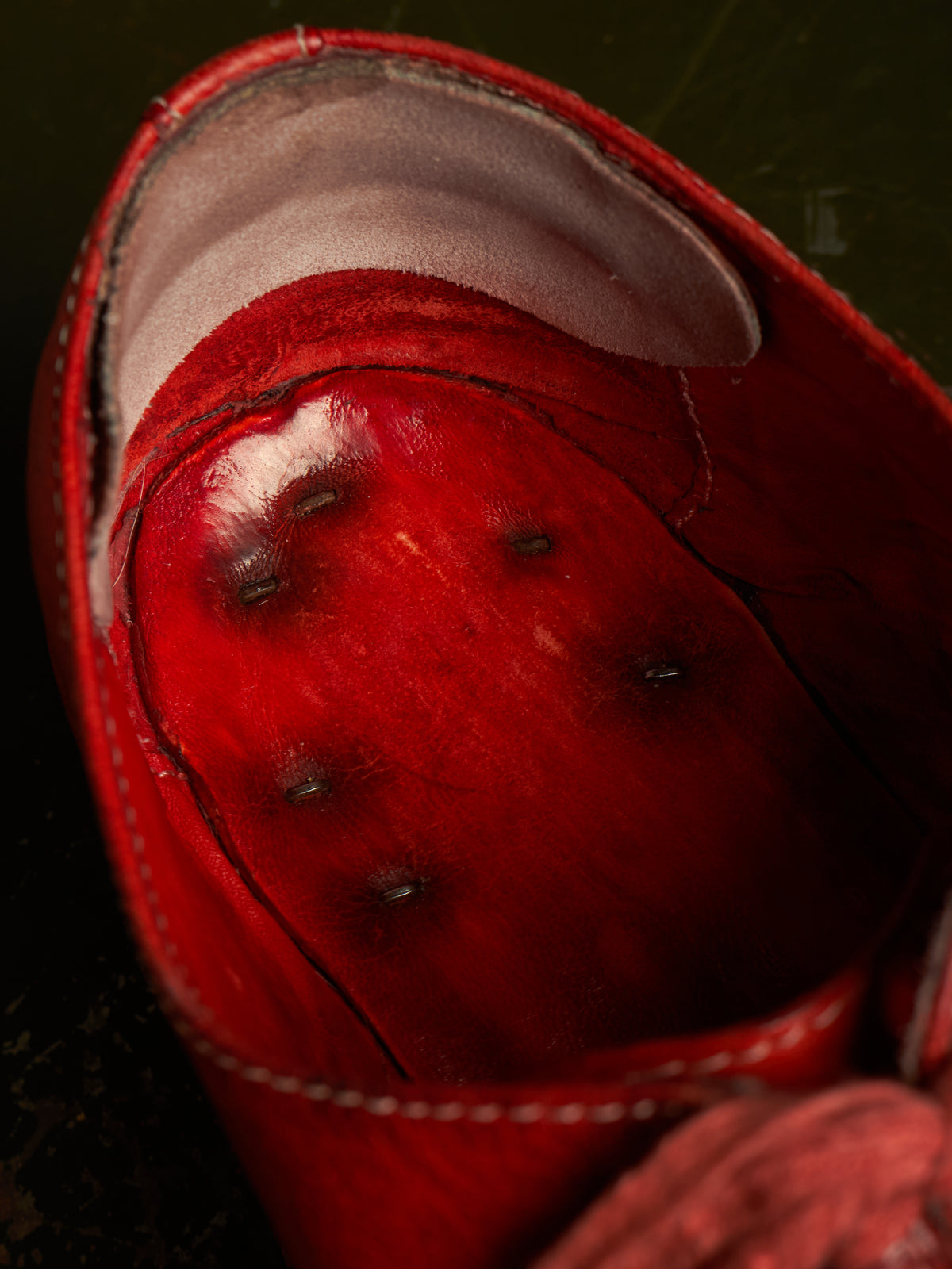 Close-up of a red leather shoe interior with visible dark spots and a light-colored footbed lining.