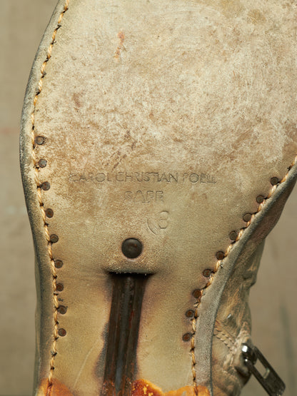 Close-up of the sole of a worn leather boot, showing the brand name Karl Christian Faber stamped in the center, with visible stitching, a pull tab, and a distressed tan-to-brown color.