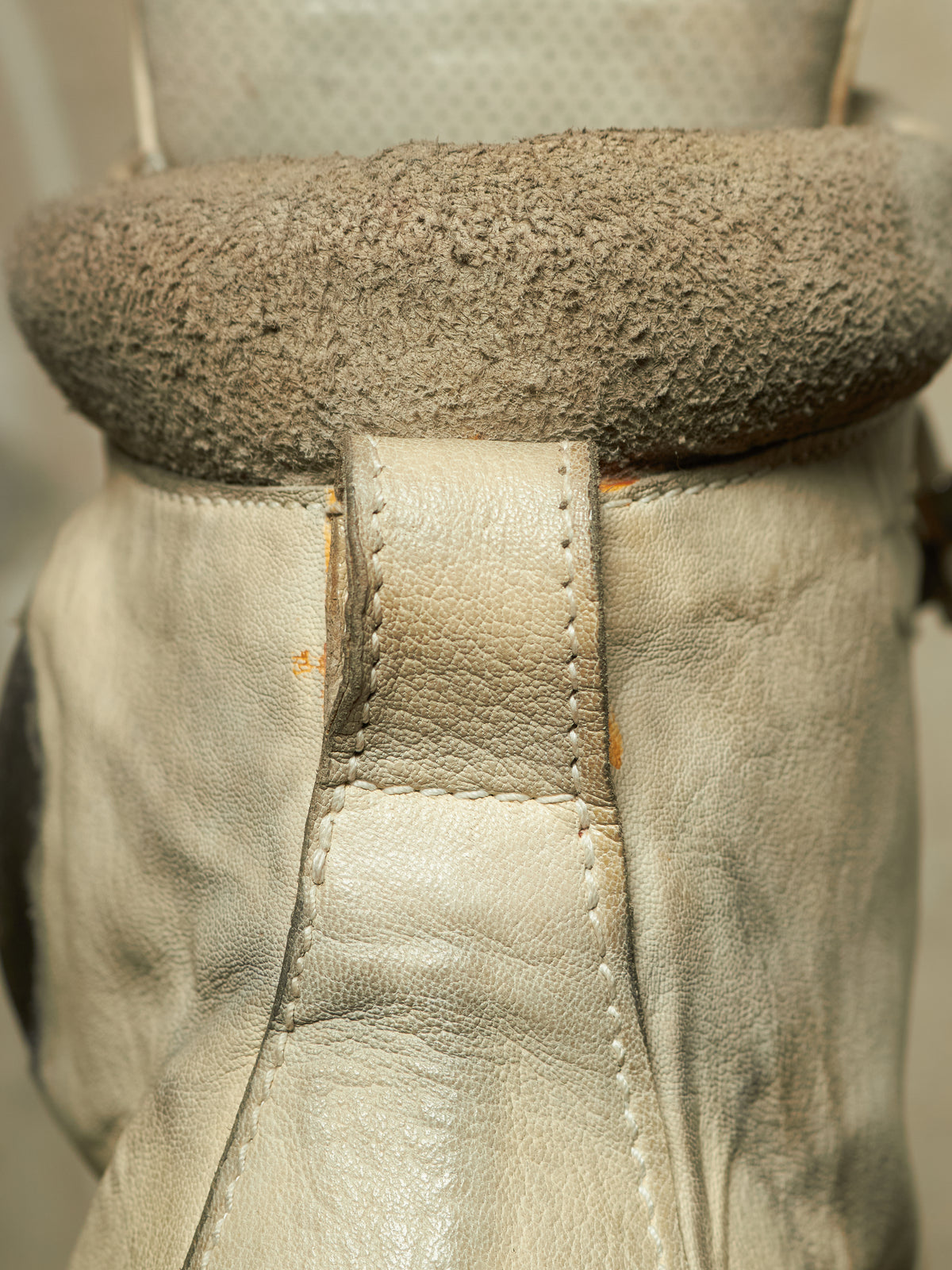 Close-up of a beige leather boot or shoe with a thick, textured taupe-brown fuzzy collar or lining.