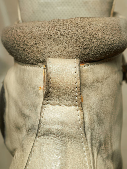 Close-up of a beige leather boot or shoe with a thick, textured taupe-brown fuzzy collar or lining.
