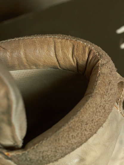Close-up detail of a worn leather boot collar showing the tan leather trim, stitching, and interior lining.