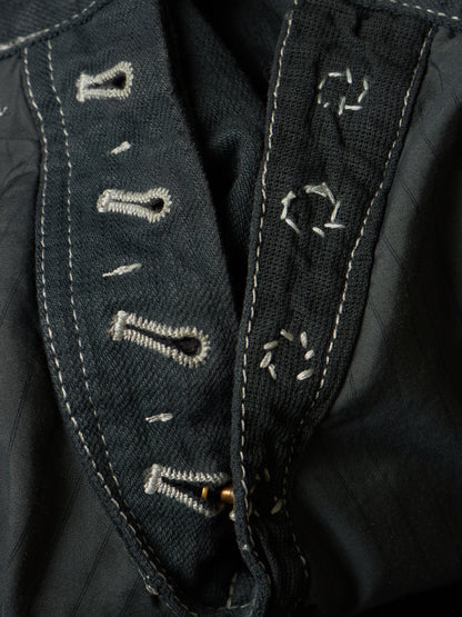 Close-up of dark denim fabric with white contrast stitching and embroidered decorative details.