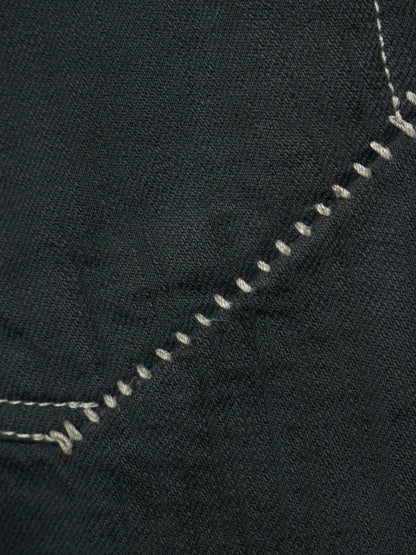 Close-up of dark charcoal gray denim fabric with white contrast stitching along a diagonal seam.