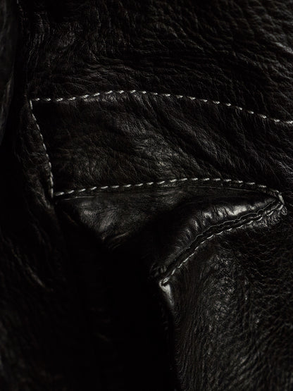 Close-up of a black leather jacket showing the texture of the leather and white contrast stitching.