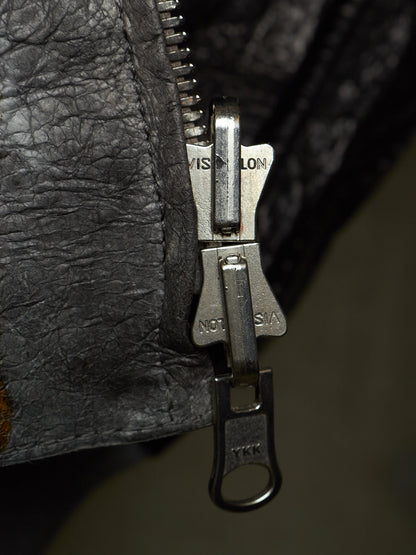 Close-up of a silver metal zipper pull with 'VISALON' and 'NOT A COPY' branding, set against a dark textured black leather background.