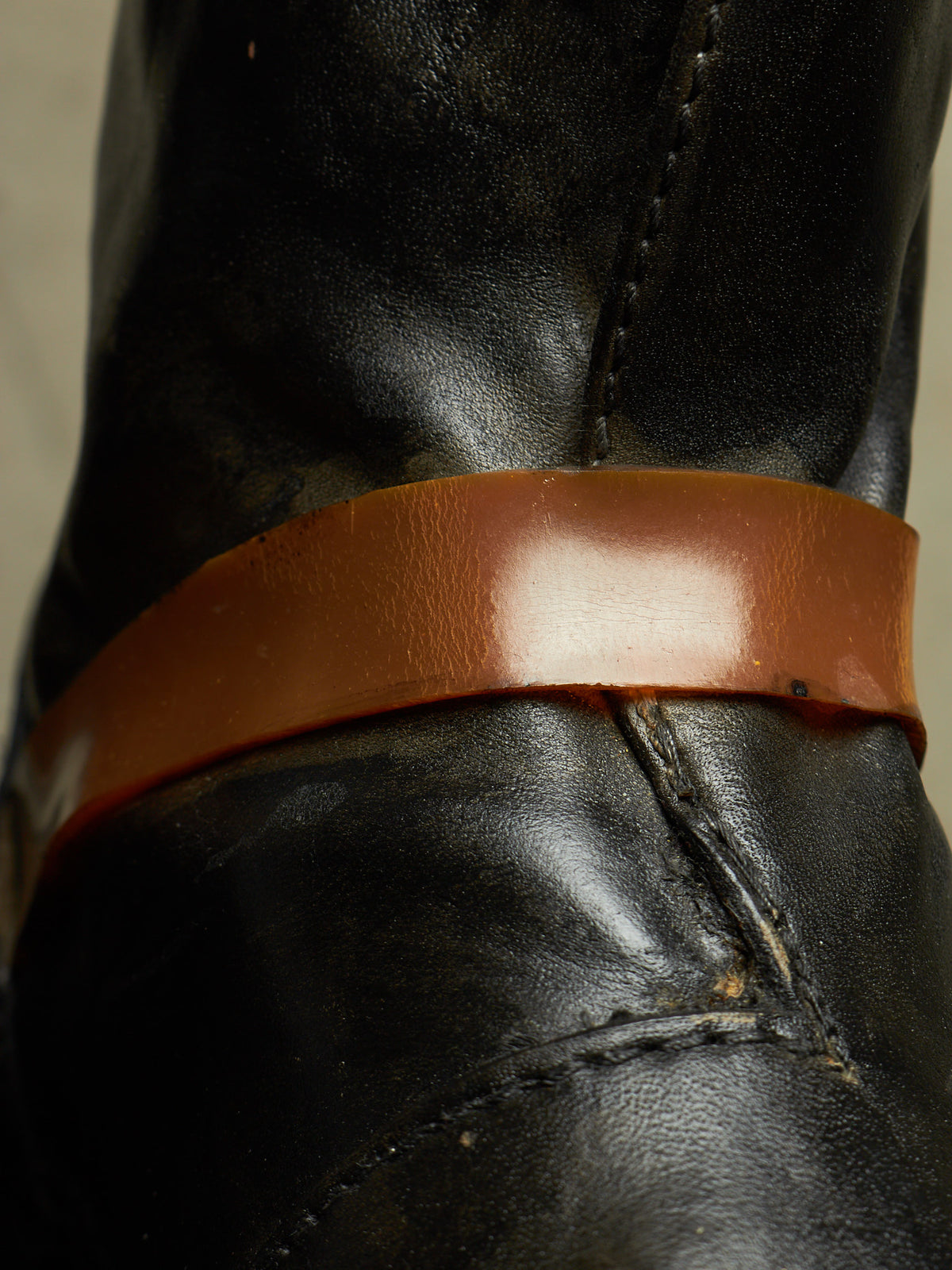 Close-up of a black leather boot with a wide, glossy brown leather band around the shaft.