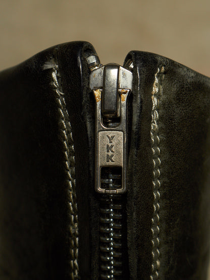 Close-up of a black leather zipper with a silver metal pull tab engraved with the letters 'YKK'.