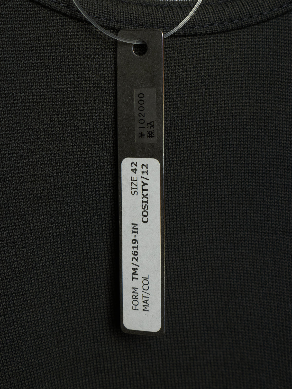 Close-up of a black ribbed knit garment with a hanging size tag reading COSIXY/ZZ, SIZE 42, and other printed details.