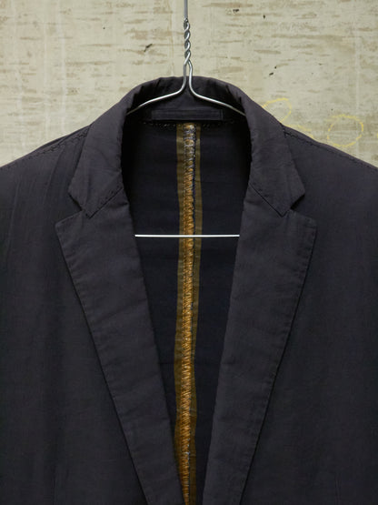 Black jacket on a hanger against a textured wall.