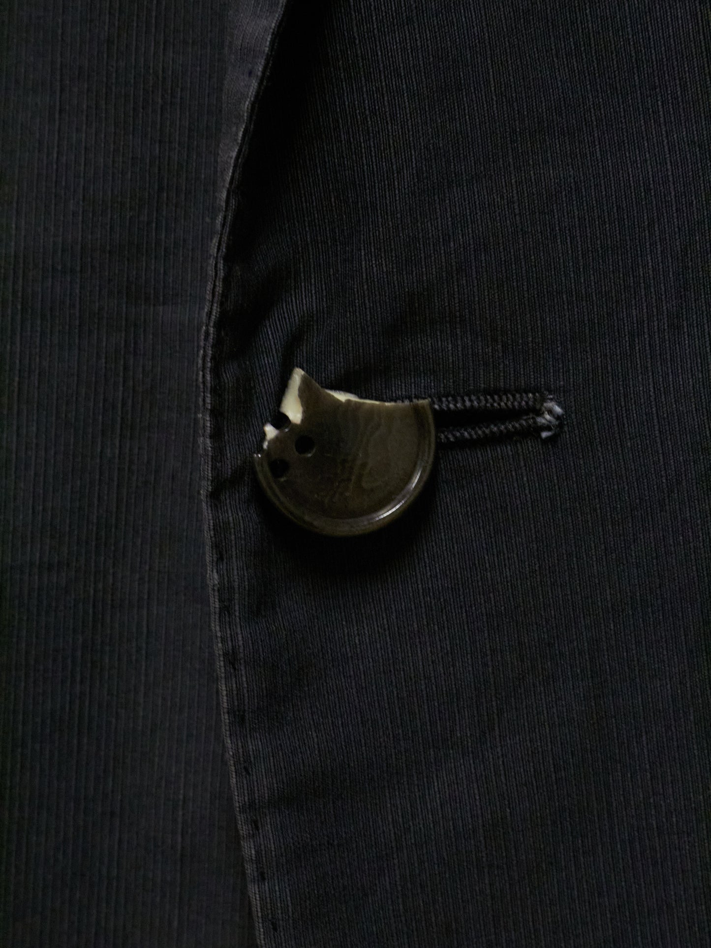 Close-up of a black jacket with a decorative button on a dark background