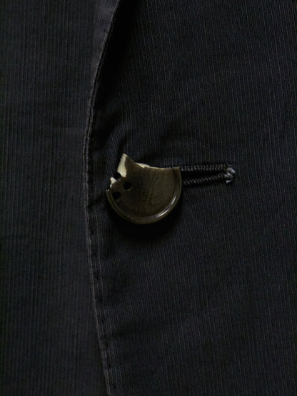 Close-up of a black jacket with a decorative button on a dark background