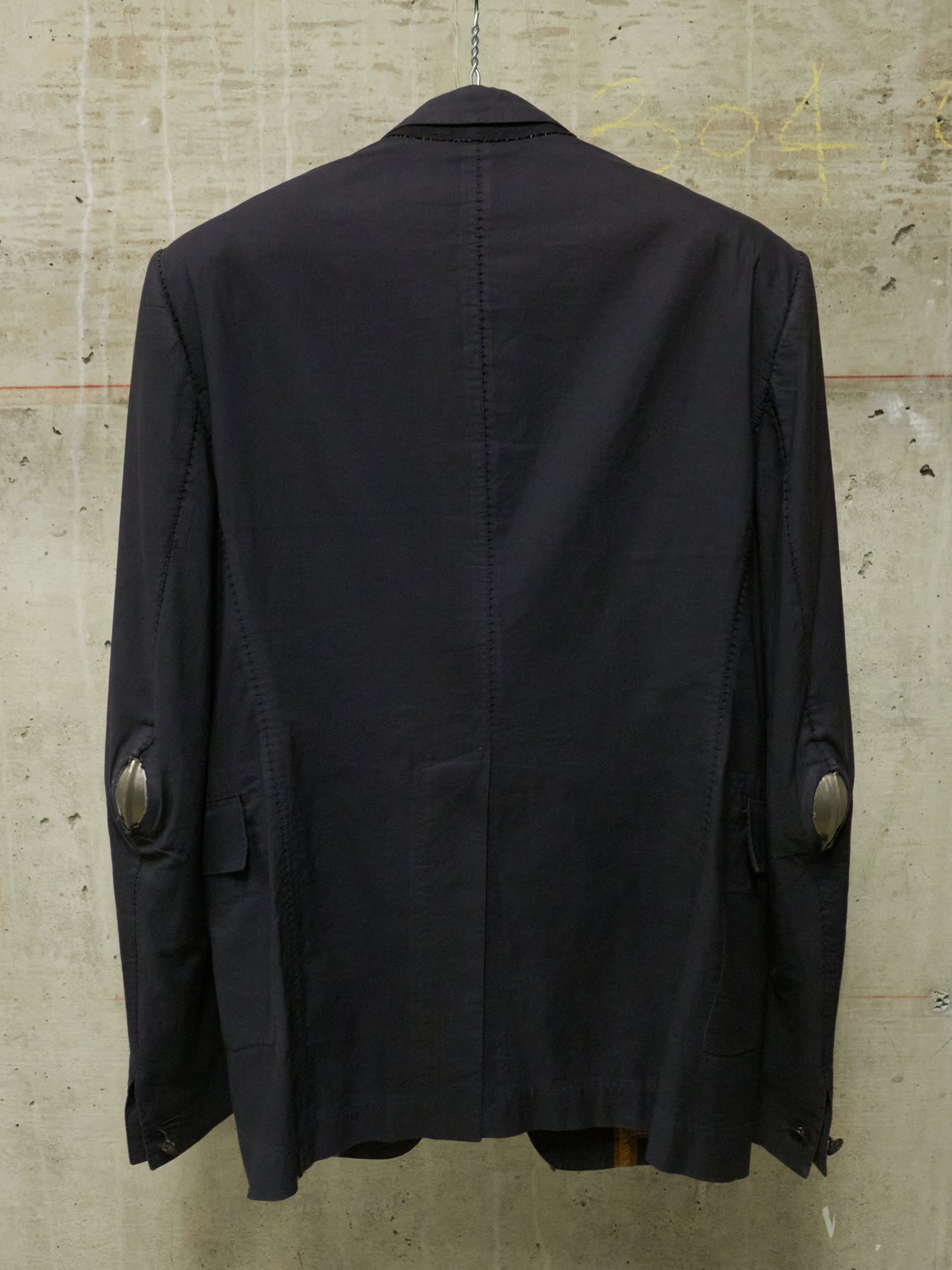 Black jacket on a hanger against a textured beige wall