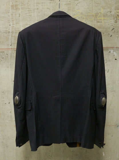Black jacket on a hanger against a textured beige wall