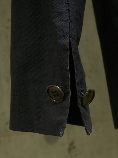 Close-up of a dark suit jacket with a button on a textured background