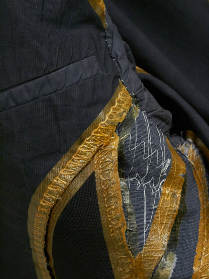 Close-up of a garment with gold embroidery and black fabric