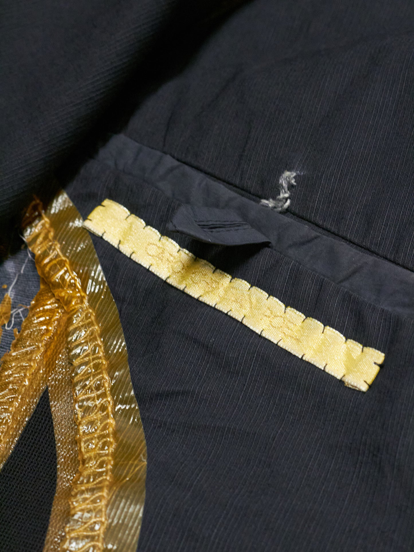 Close-up of a black garment with gold trim and decorative elements.