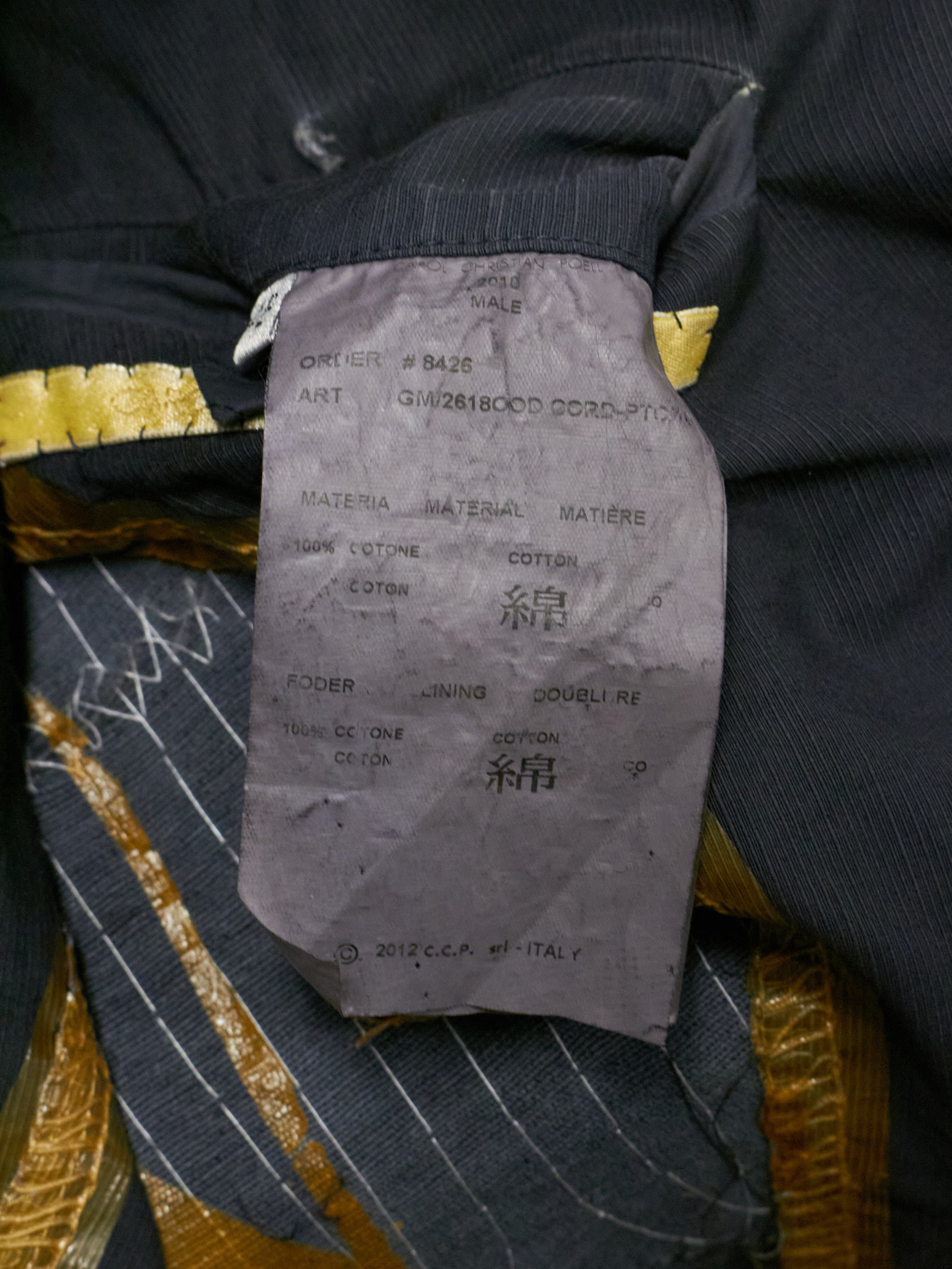 Close-up of a clothing label on a garment with gold and black details.