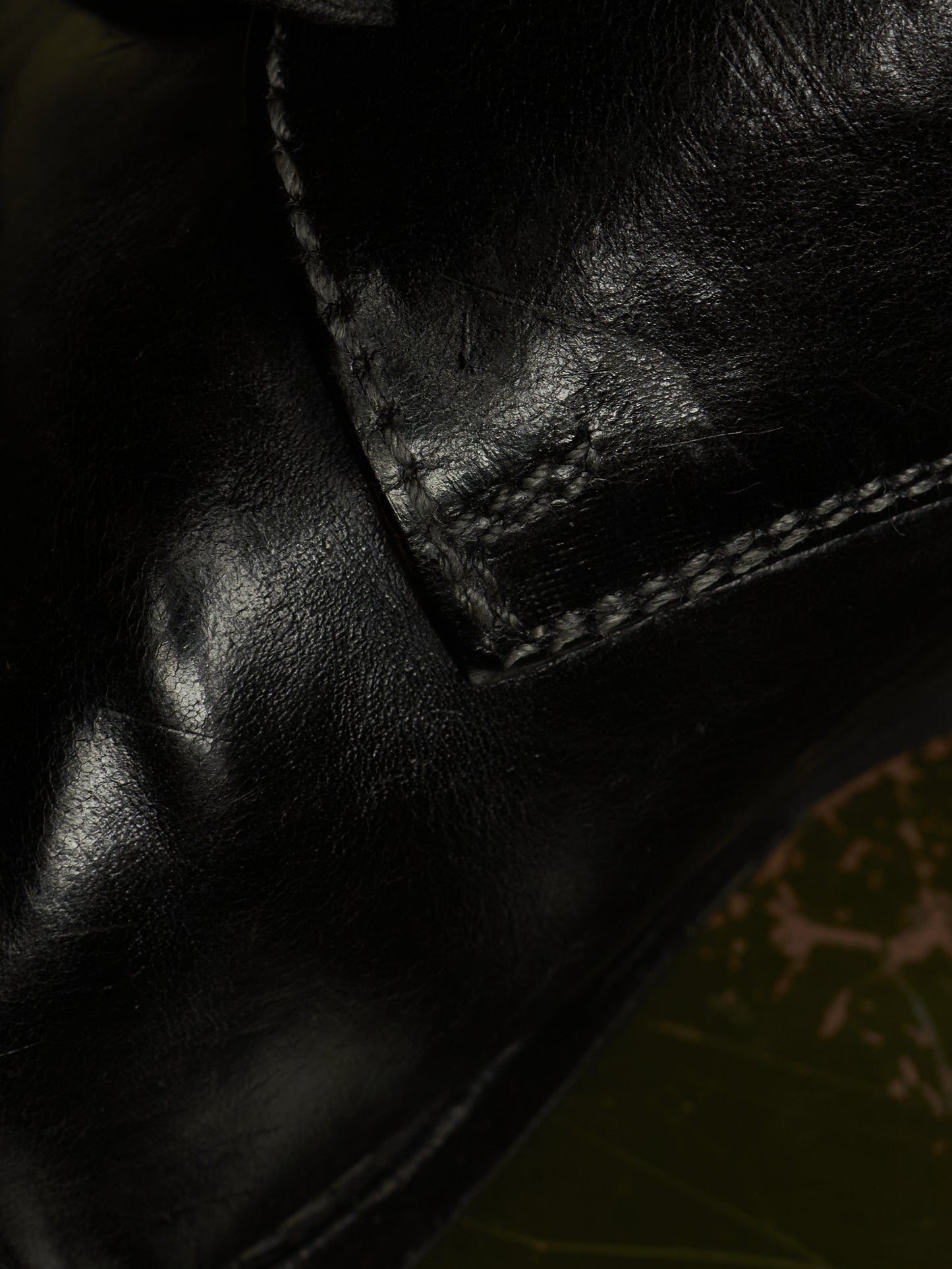 Close-up of a black leather boot showing the texture of the leather and the stitching of a welt panel.