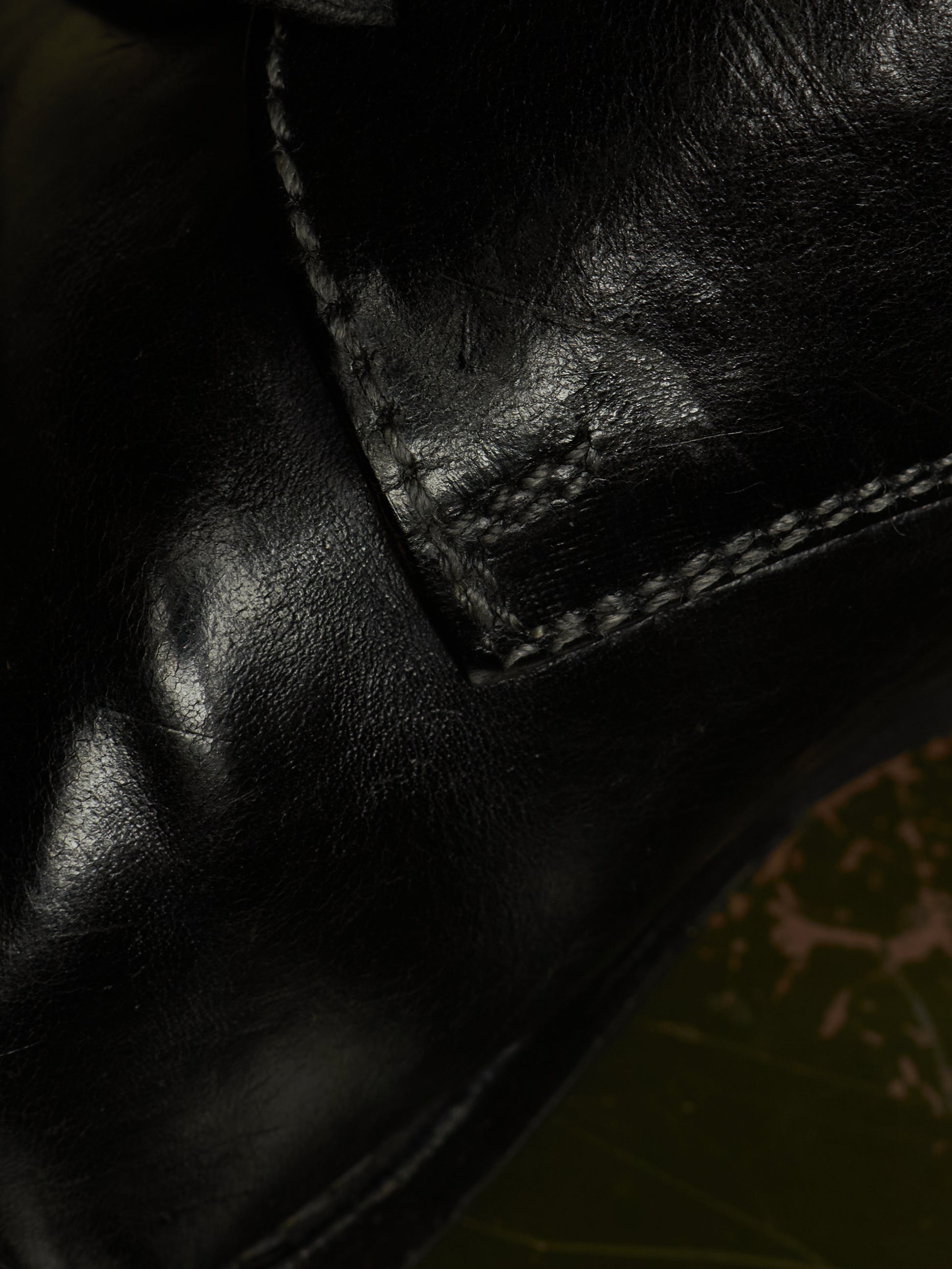 Close-up of a black leather boot showing the texture of the leather and the stitching of a welt panel.