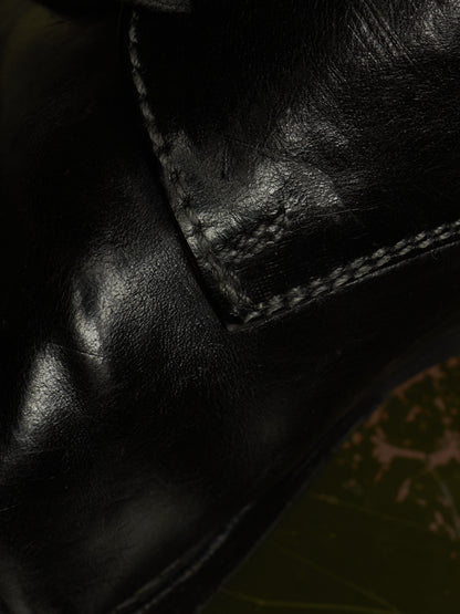 Close-up of a black leather boot showing the texture of the leather and the stitching of a welt panel.