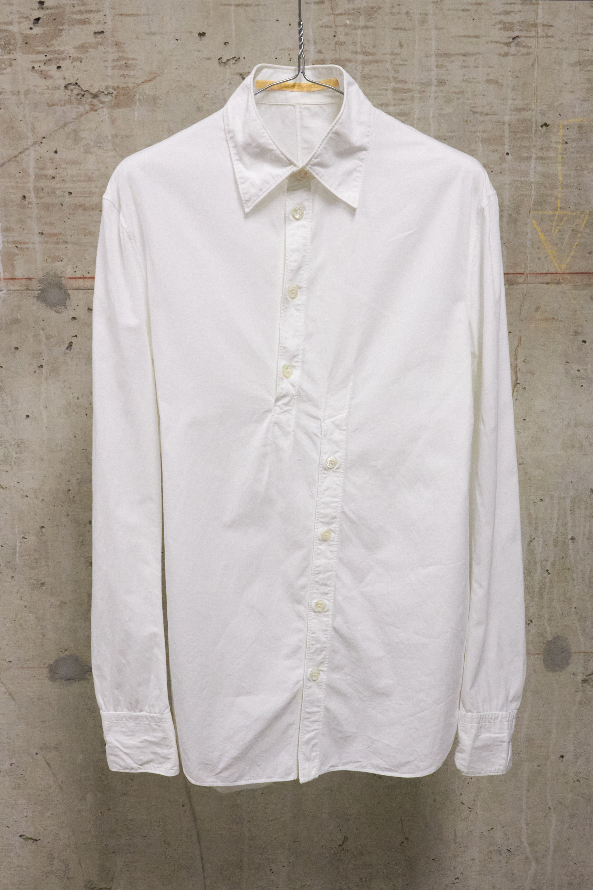 White shirt on a hanger against a textured wall