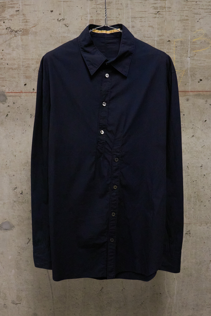 Navy blue shirt on a hanger against a textured beige wall