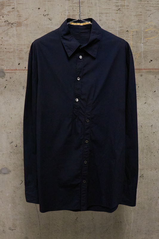 Navy blue shirt on a hanger against a textured beige wall