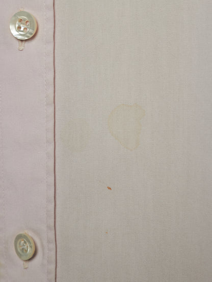 Close-up of a light beige or off-white linen-like fabric with a vertical seam and two visible buttons on the left edge. There are faint yellowish stains or marks on the fabric surface.