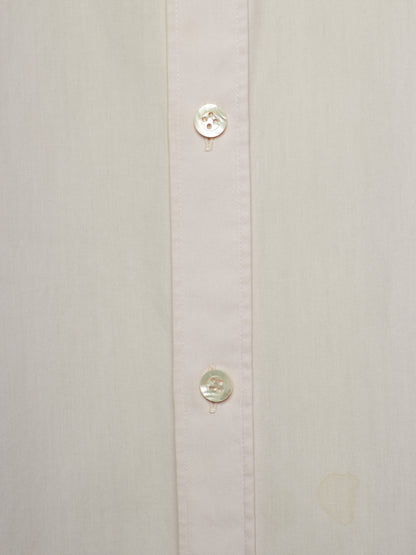 Close-up of a light cream or off-white button-down shirt showing the front placket with two round buttons.