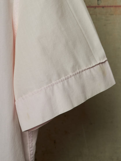 Close-up detail of a light pink garment sleeve showing the hem and fine stitching against a neutral background.