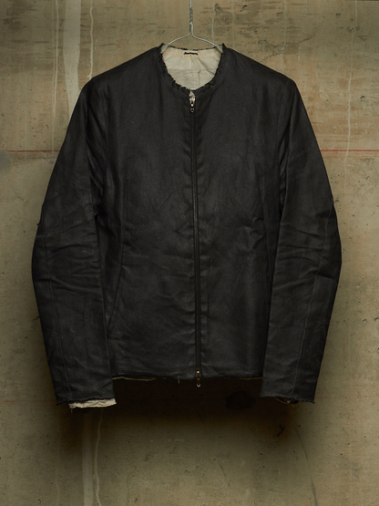 A black zip-up jacket with a light beige lining, hanging on a wire hanger against a textured concrete wall.