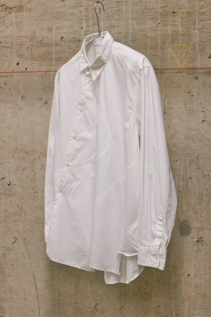 White shirt hanging on a hook against a textured concrete wall