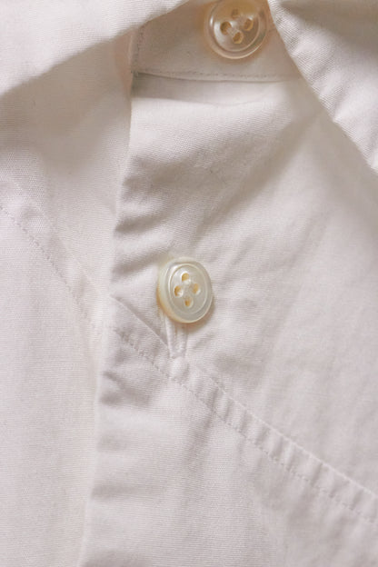 Close-up of a light-colored shirt with buttons on a matching fabric background