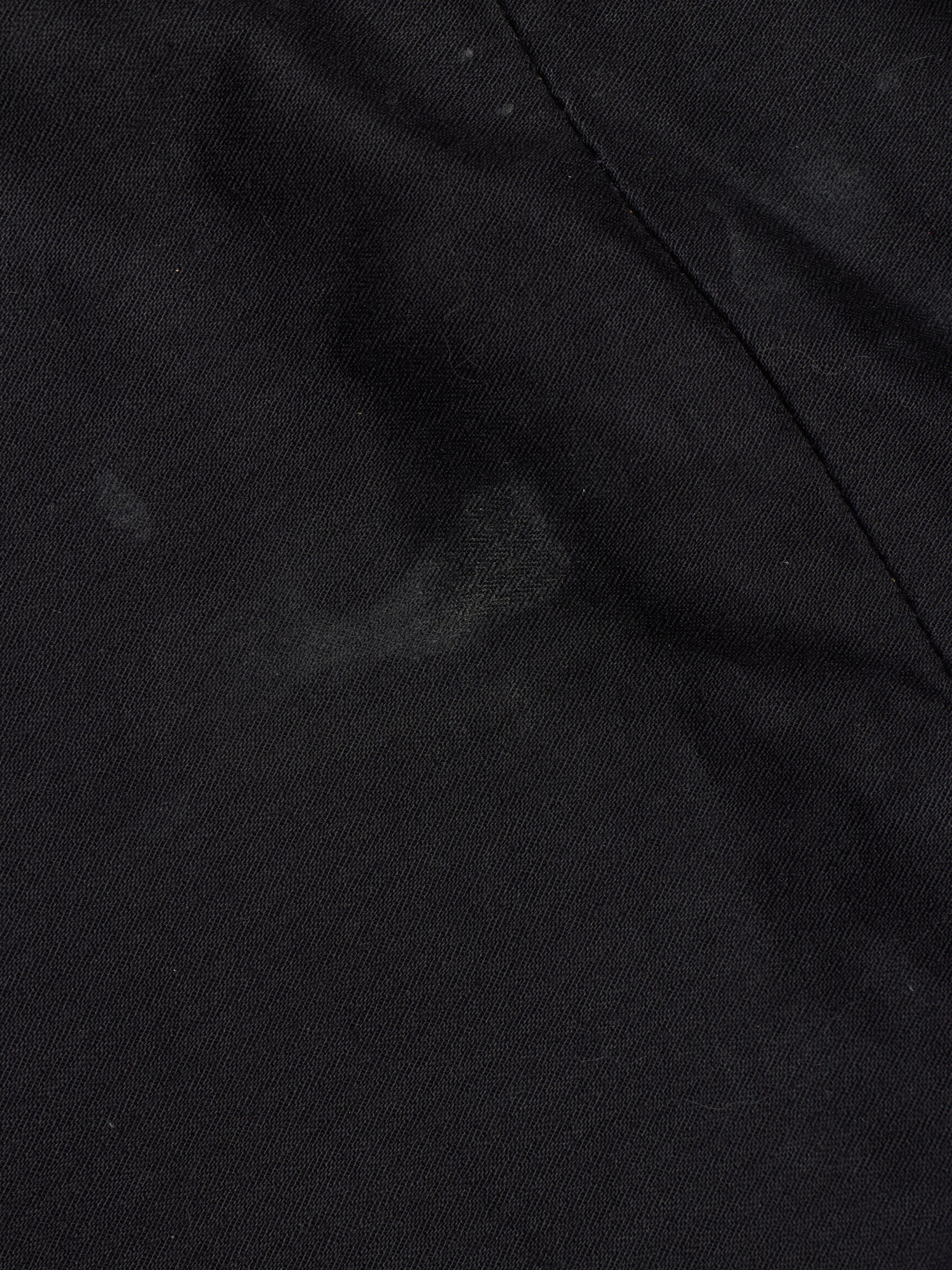 A close-up of black fabric with a visible seam and a slightly mottled texture.